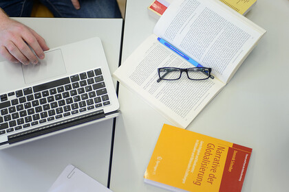 Bild von oben auf einen Laptop und Lehrbücher