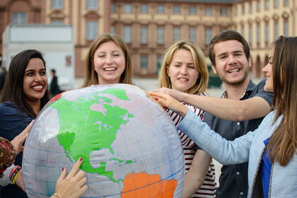 Studierende halten gemeinsam einen großen Globus
