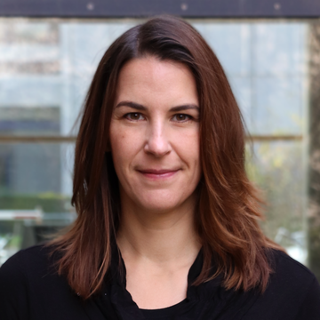 Claudia Schilings hat lange braune Haare. Sie trägt ein schwarzes Oberteil und lächelt in die Kamera.